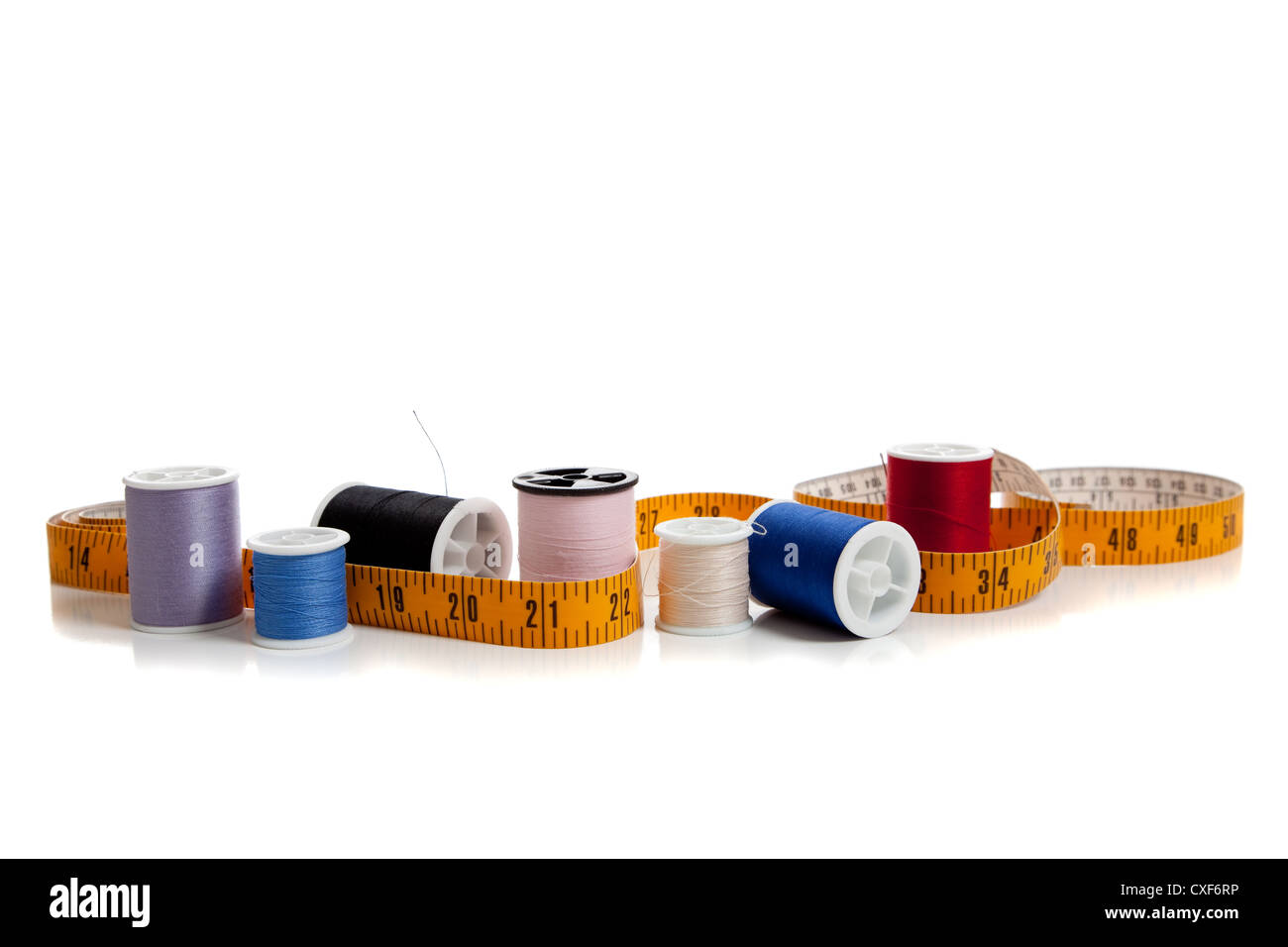 row of spools of thread with a tape measure on a white background Stock ...