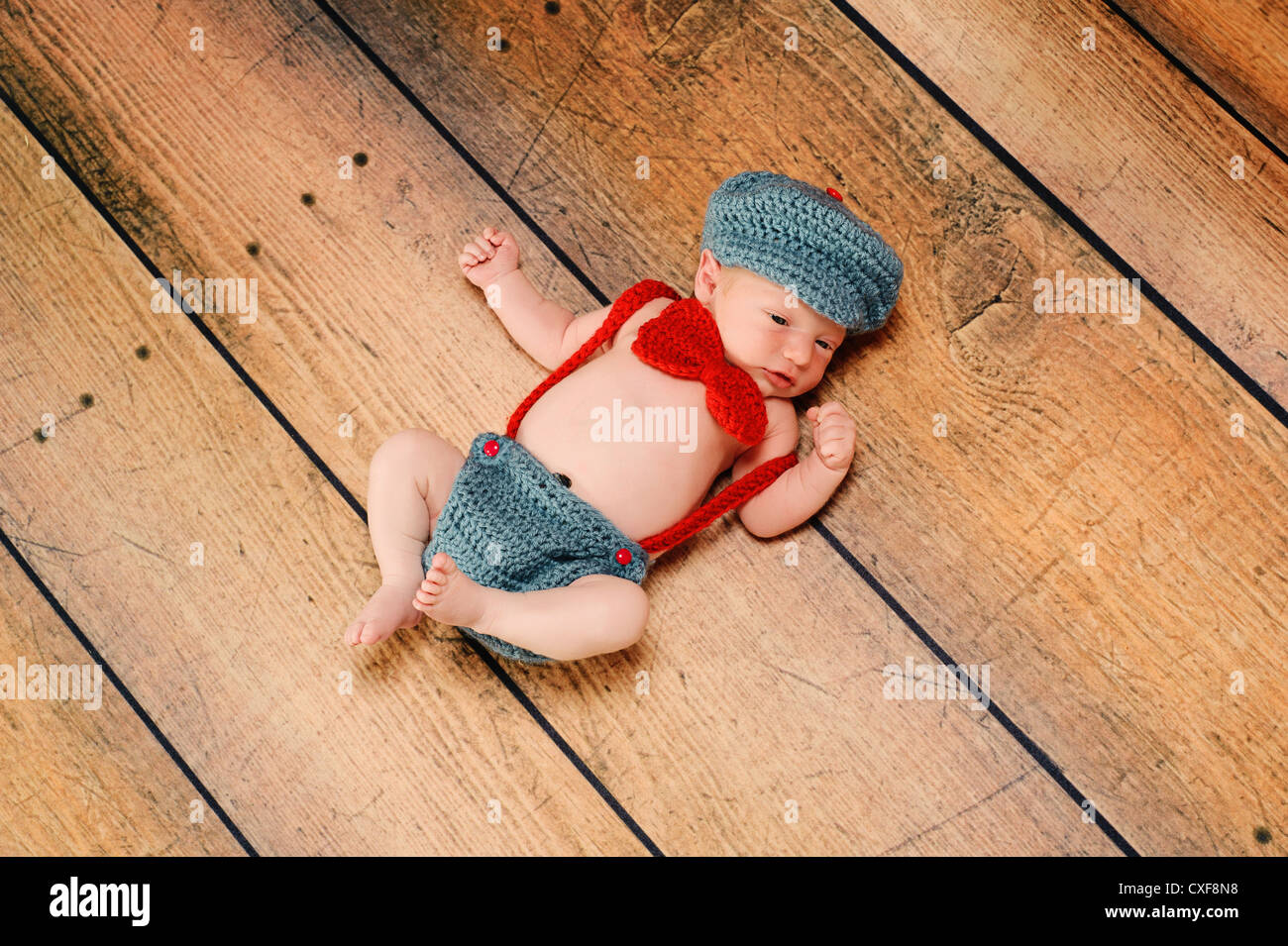 11 day old newborn baby boy wearing a vintage inspired gray and red 'little man' suit with suspenders, bow tie and hat. Stock Photo