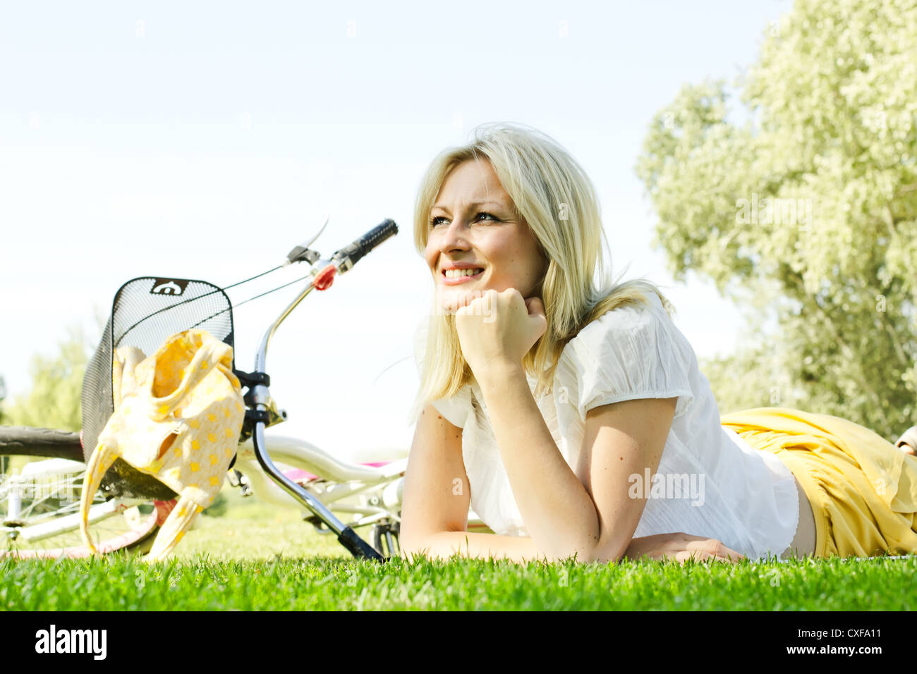 Happiness young blond woman relaxing on green grass after cycling Stock ...