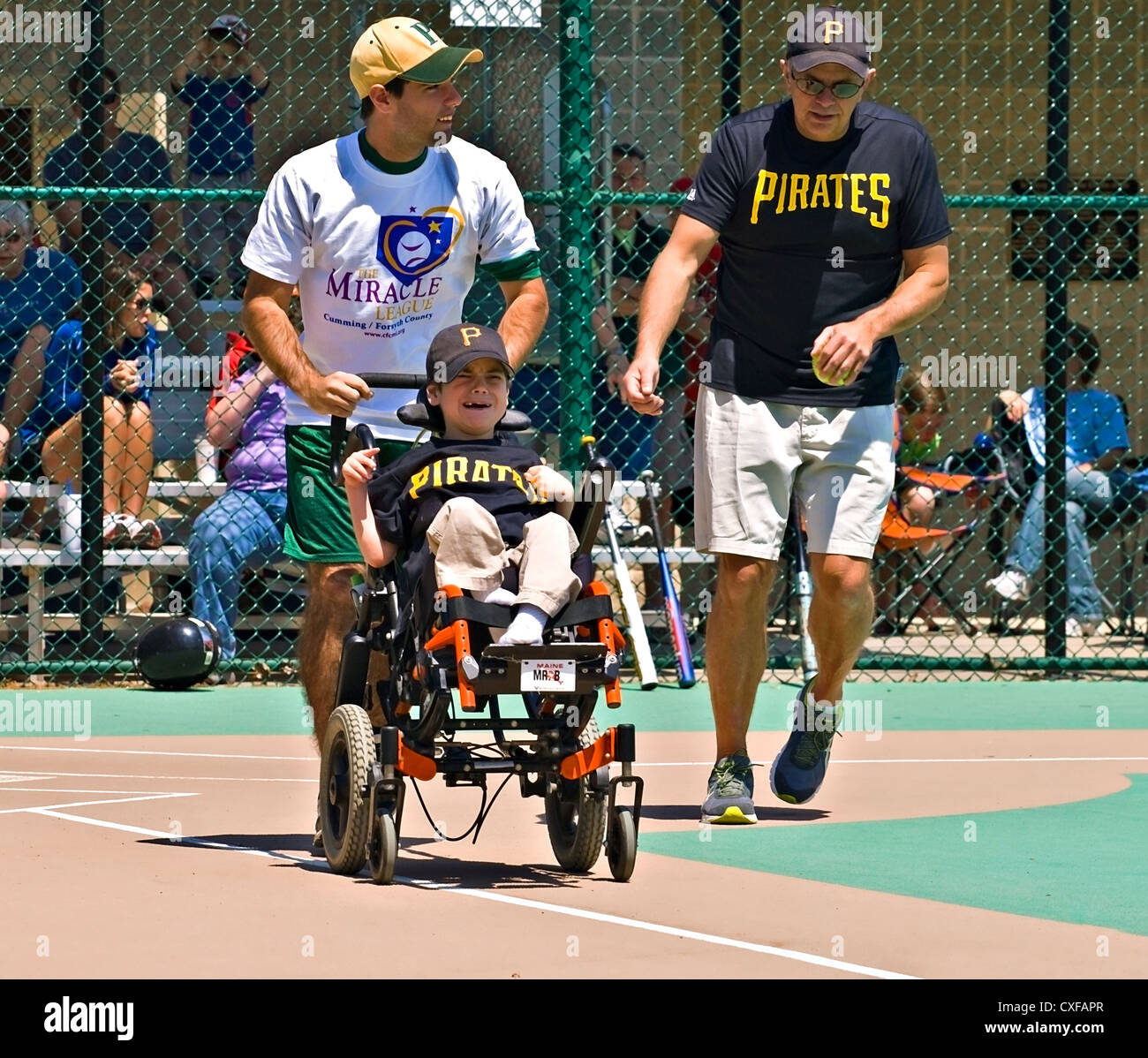 Player and coaches on a softball team in the Miracle League making a run for first base after a hit. Stock Photo