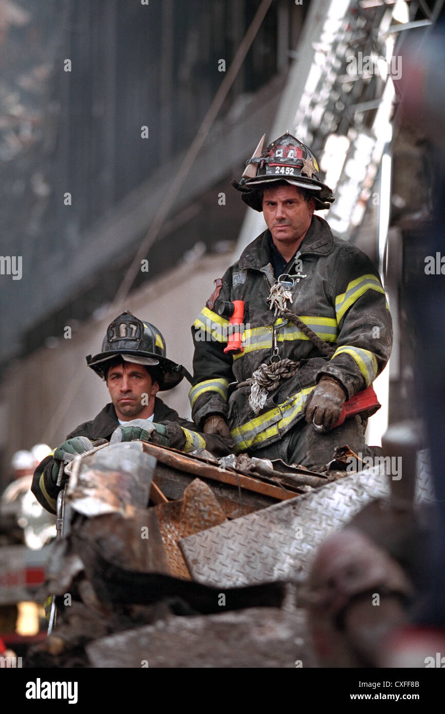 Firefighters look on as US President George W. Bush addresses rescue workers at the destroyed World Trade Center September 14, 2001 in New York City. Bush addressed recovery workers and rallied the nation following terrorist attacks. Stock Photo
