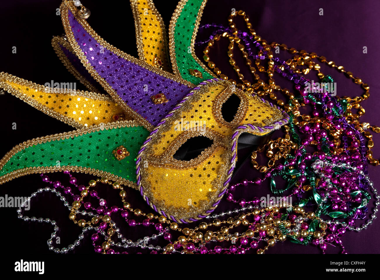 A Mardi Gras jester mask and beads on a black background Stock Photo