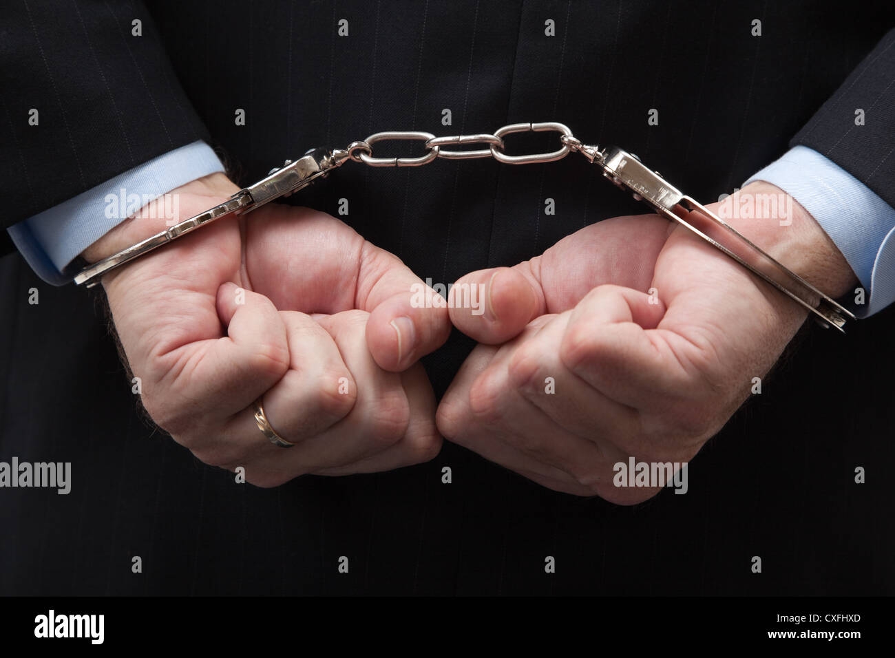 Man in a business suit with hands in hand cuffs signifying a white collar crime Stock Photo