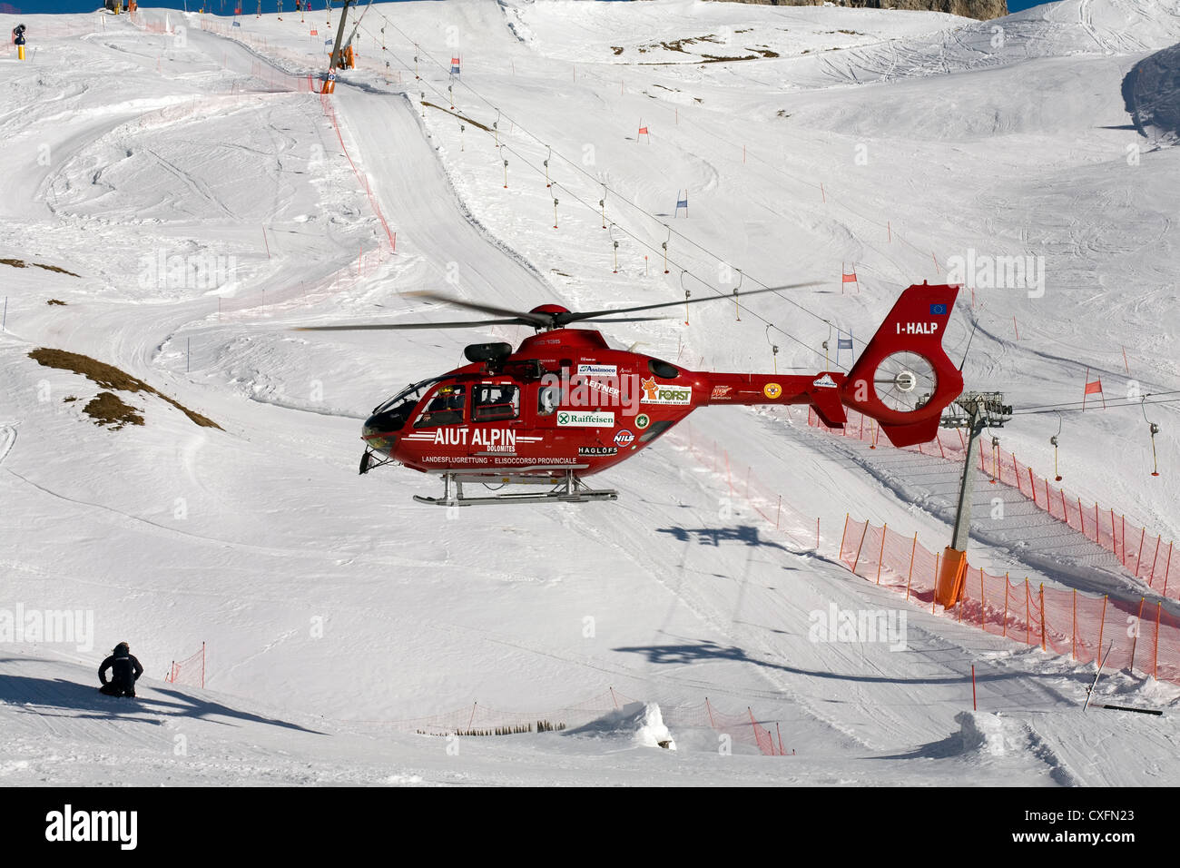 Air Ambulance attending a serious skiing accident on a piste in Selva Val Gardena Dolomites Italy. Helicopter type EC 135 Stock Photo