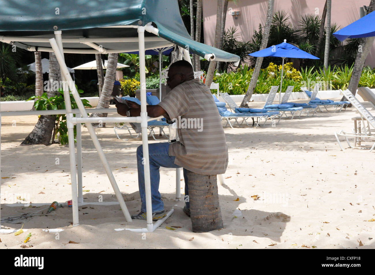 Barbados Tropical Beach local sitting in shade Stock Photo