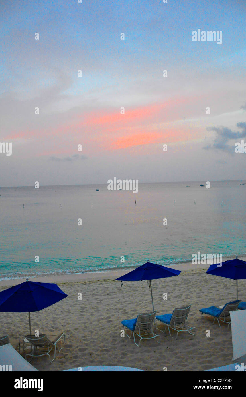 Royal Pavilion Barbados tropical beach vacation, blue sun umbrellas pink sky Stock Photo
