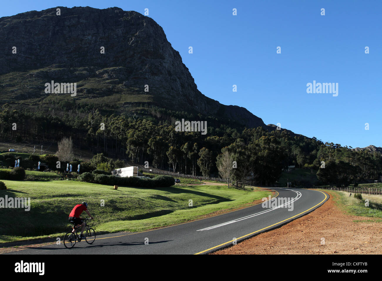 A cyclist rides up Franschhoek Pass, South Africa Stock Photo