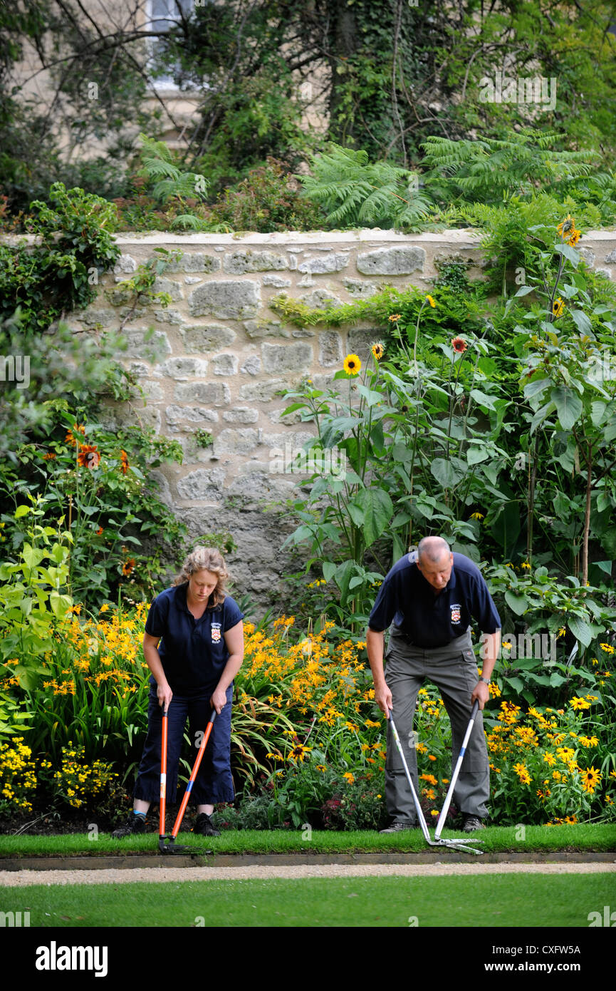 Gardeners with edging shears working along a path at Worcester College Oxford Stock Photo