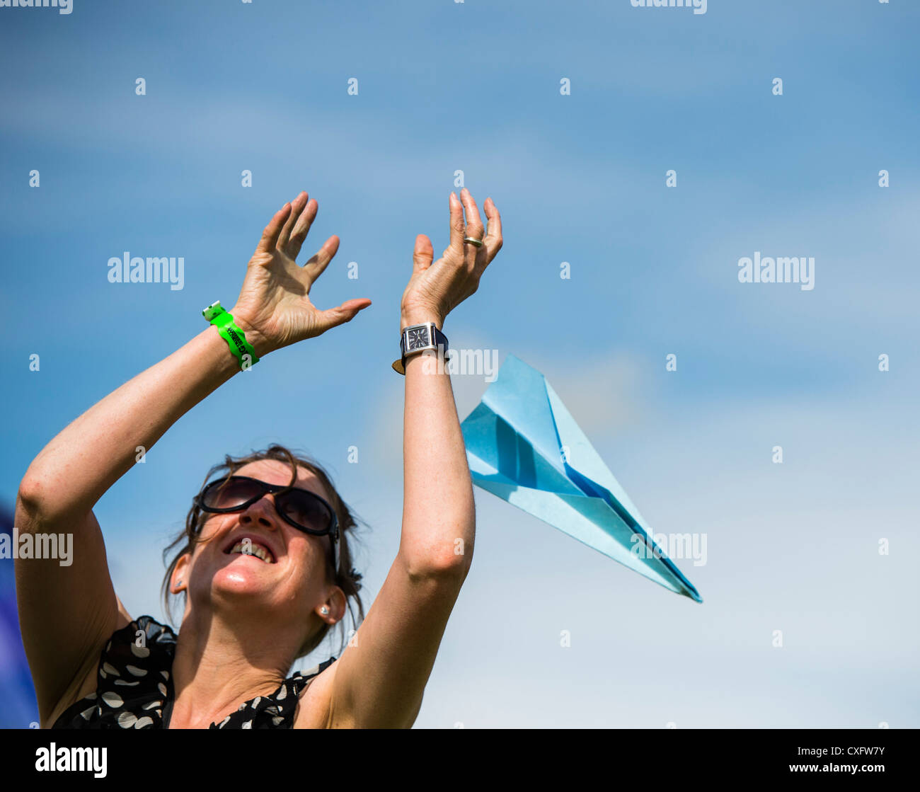 A young woman trying to catch a paper airplane at the Big Tribute Music festival, Wales UK August 2012 Stock Photo