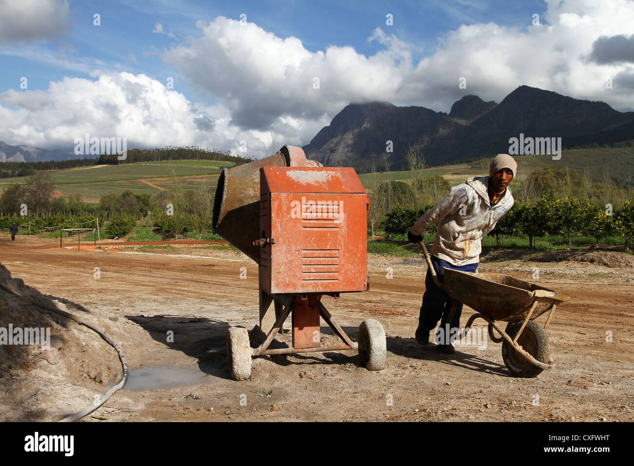 Construction worker with wheel barrow at cement mixer near Stellenbosch, South Africa Stock Photo