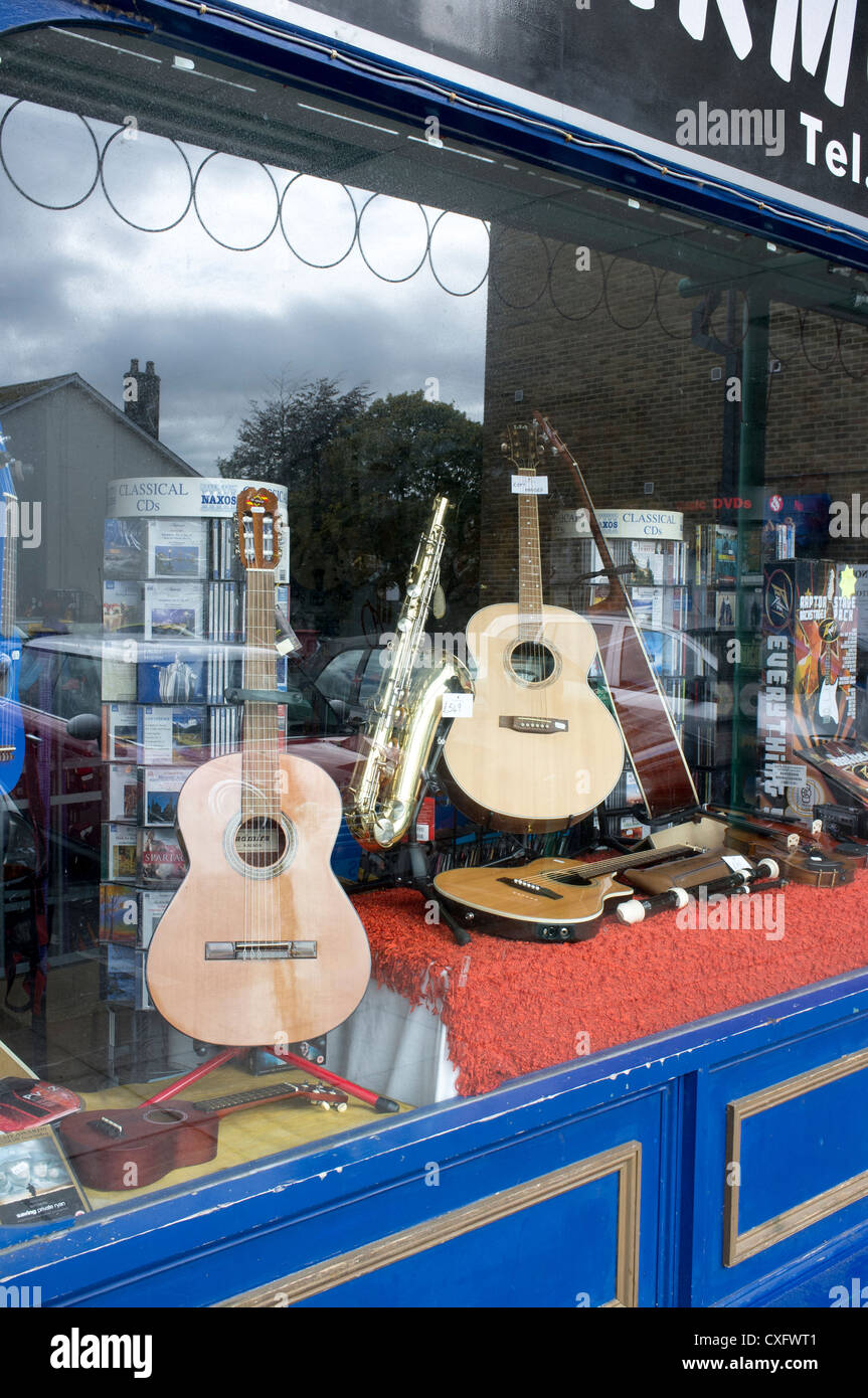 Musical instruments for sale in a music shop window. Guitars and Saxophone Stock Photo