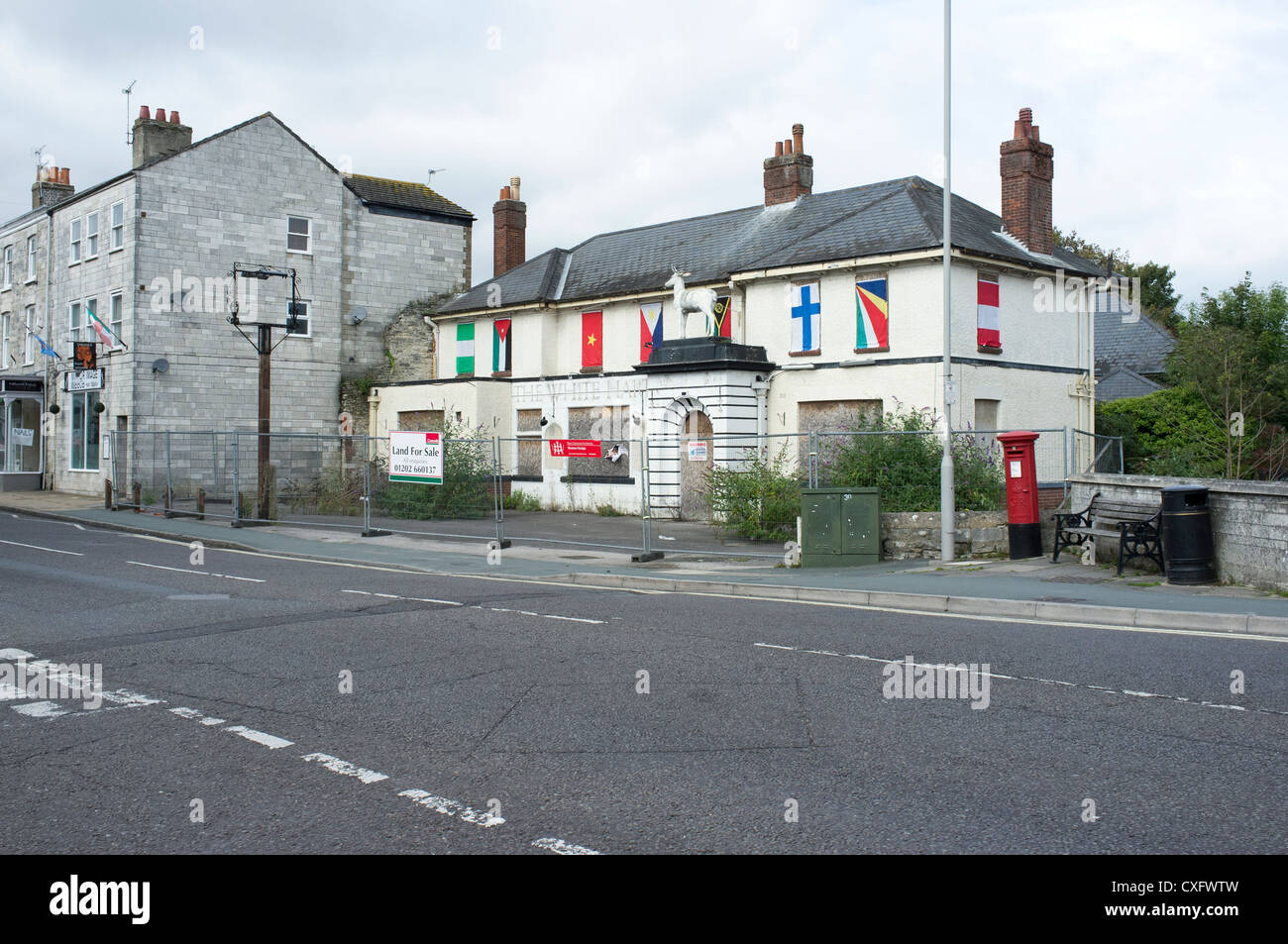 Closed down empty pub with boarded up windows and international flags hung over upstairs windows Stock Photo