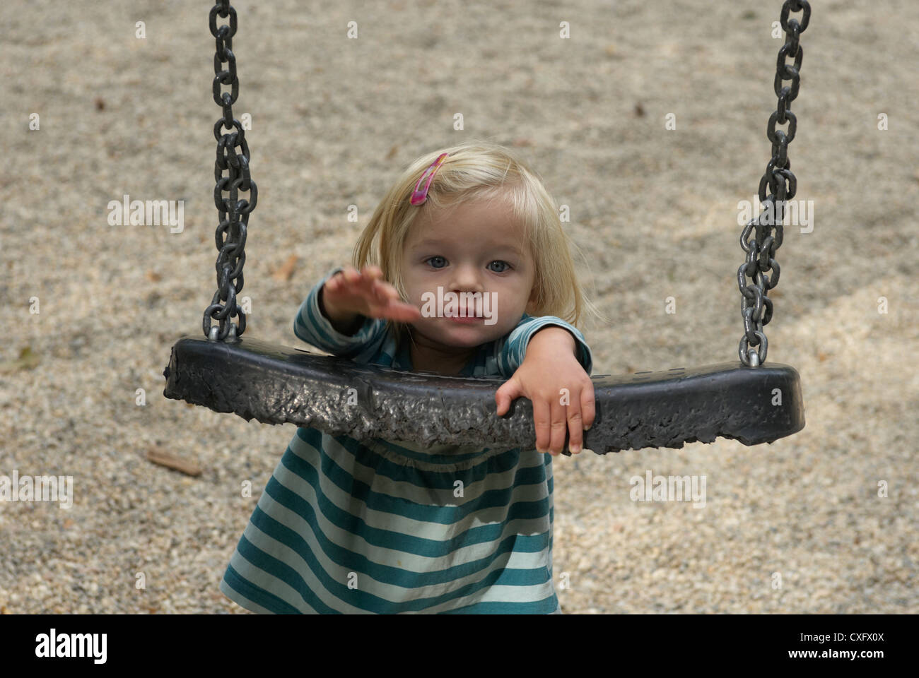 Blond child baby girl having a swing outside summer Stock Photo