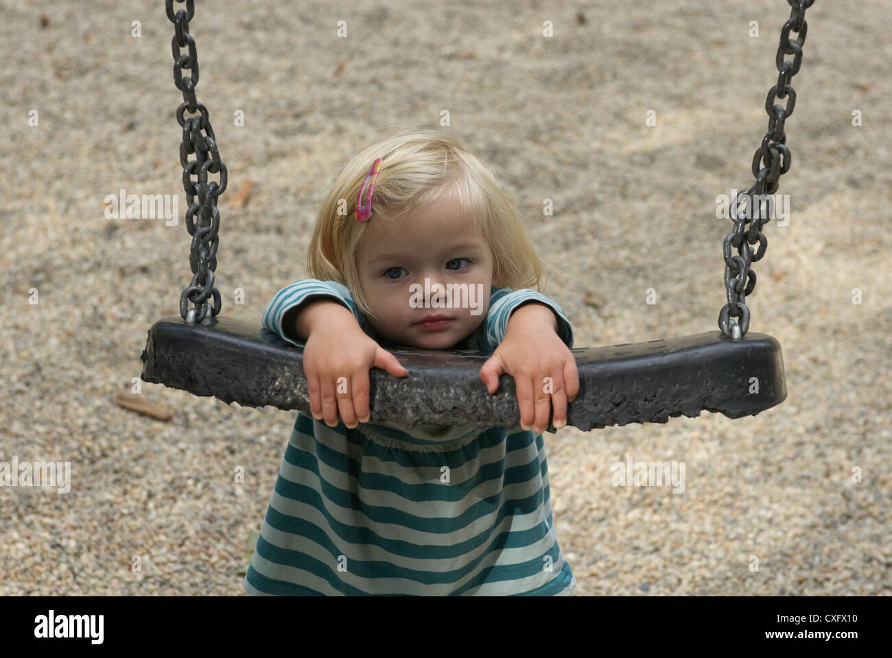 Blond child baby girl having a swing outside summer Stock Photo