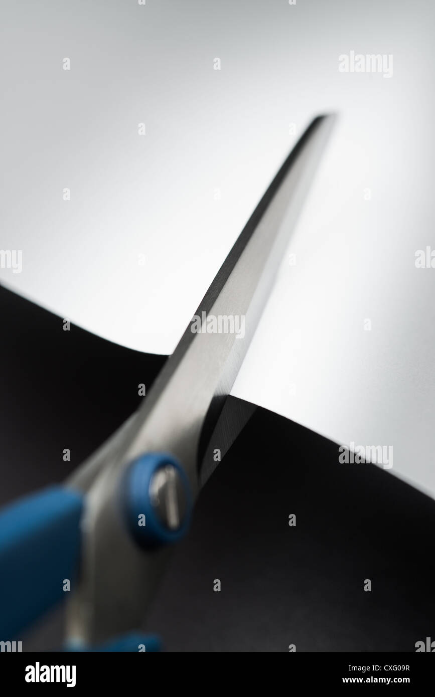 A pair of scissors cutting snipping a piece of paper Stock Photo Alamy