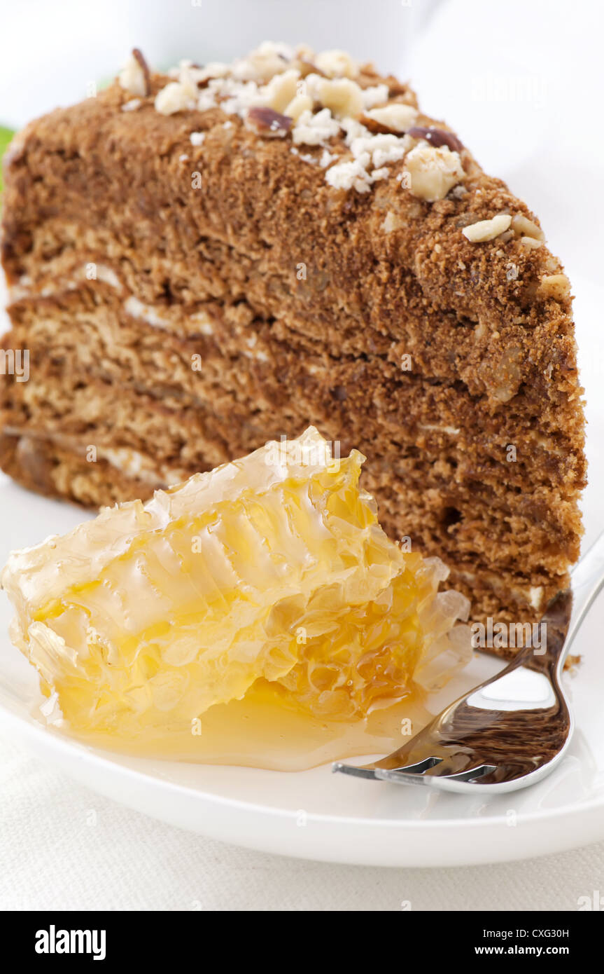Honey cake with honeycomb as closeup on a white plate Stock Photo