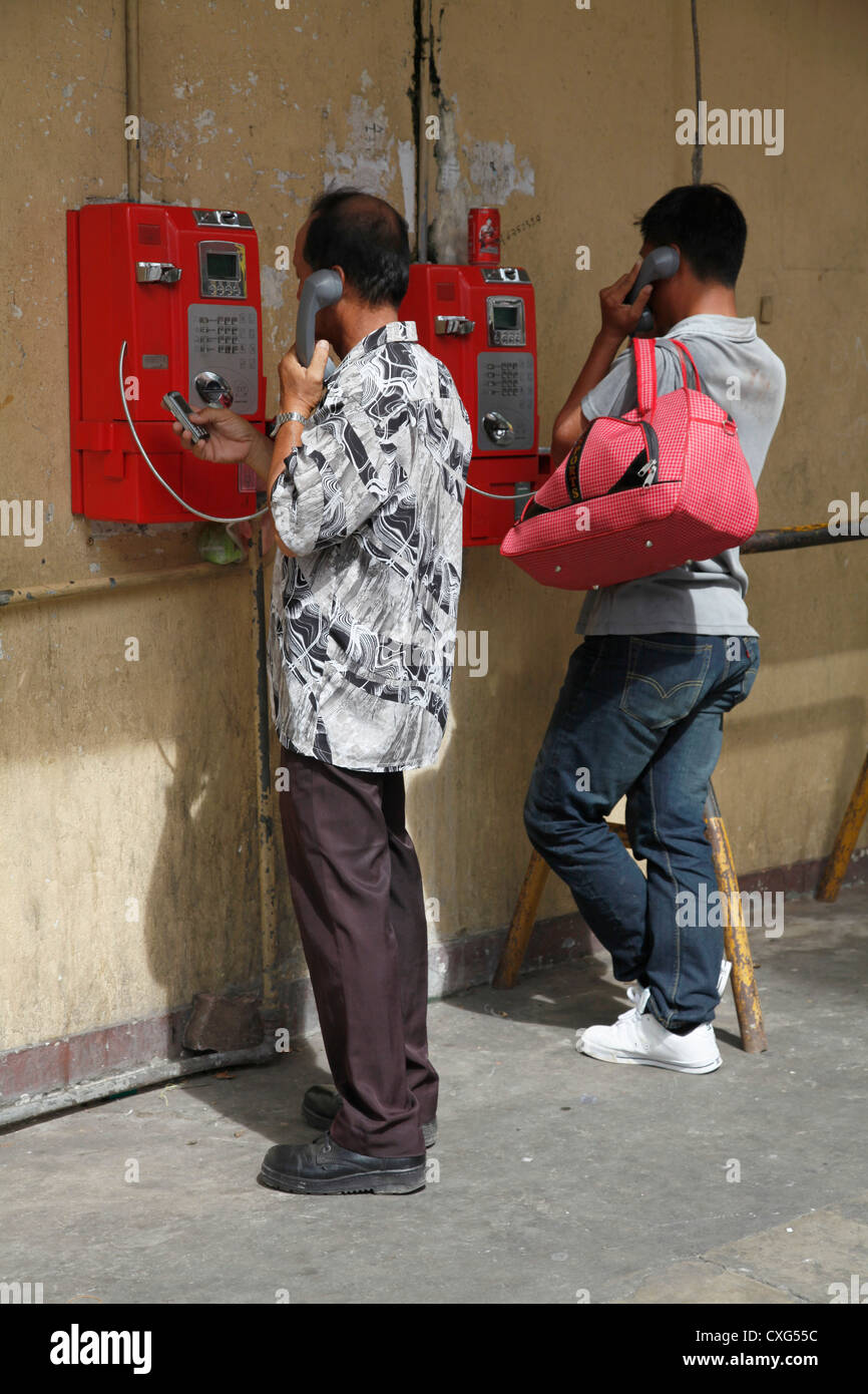 Men talking on public payphones in Kuala Lumpur, Malaysia Stock Photo