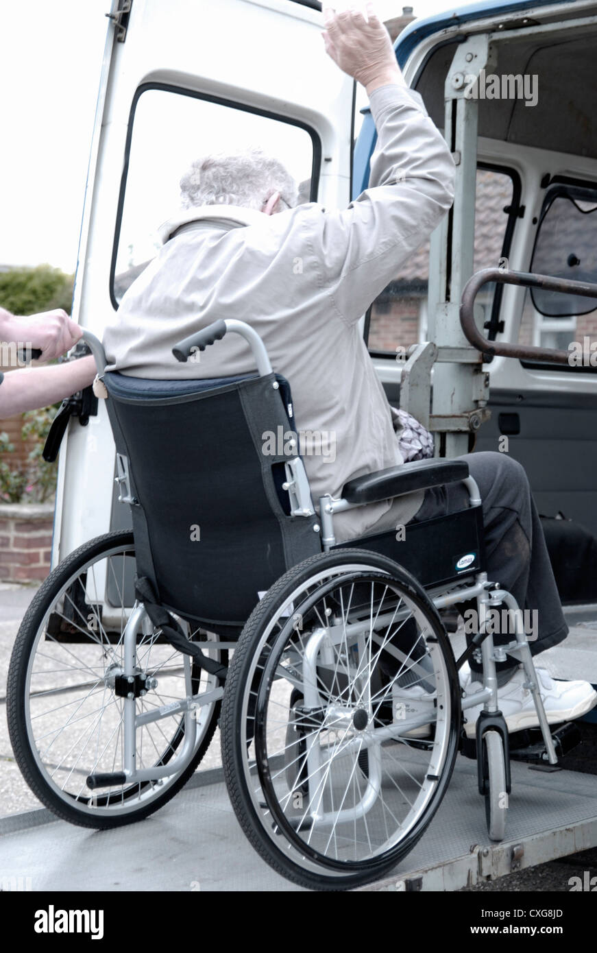 Elderly man in a wheelchair on platform ramp lift of a specialised adapted vehicle voluntary service for transporting disabled Stock Photo
