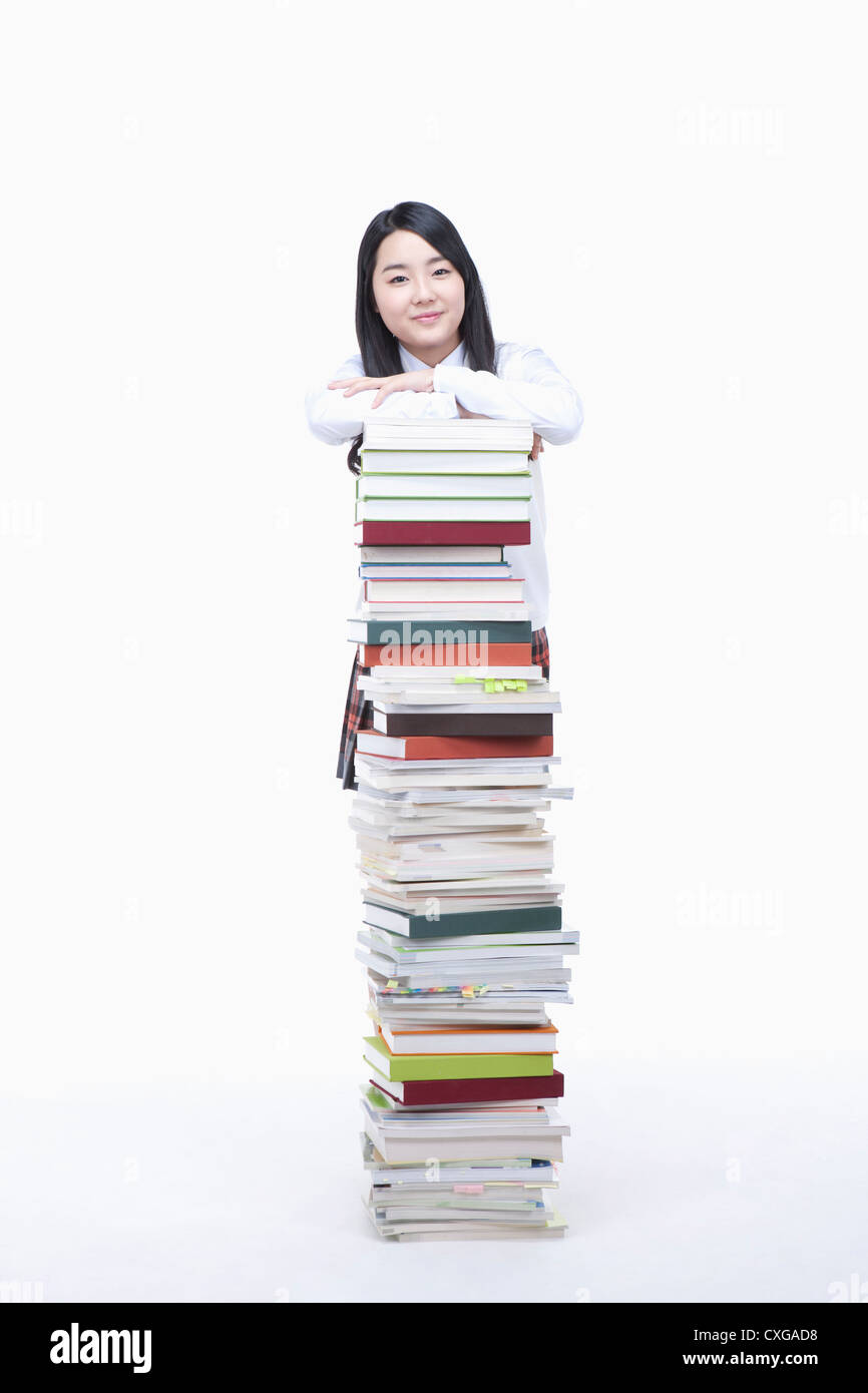 schoolgirl standing behind a stack of books Stock Photo - Alamy