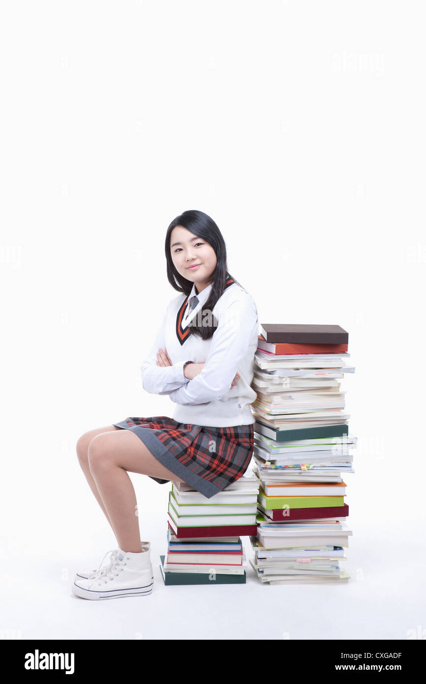 schoolgirl sitting on a stack of books Stock Photo - Alamy