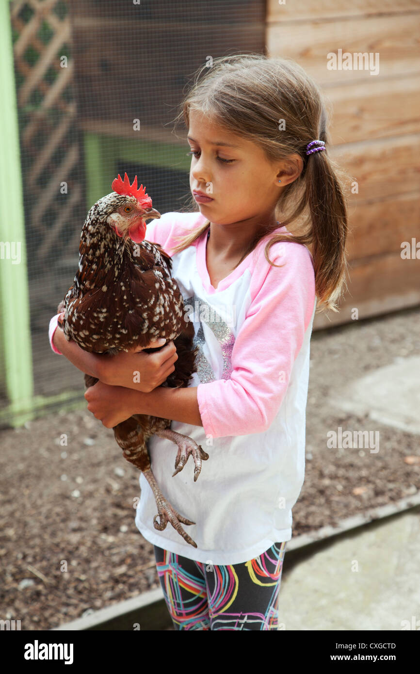 A six year old girl is holding a pet chicken. Stock Photo