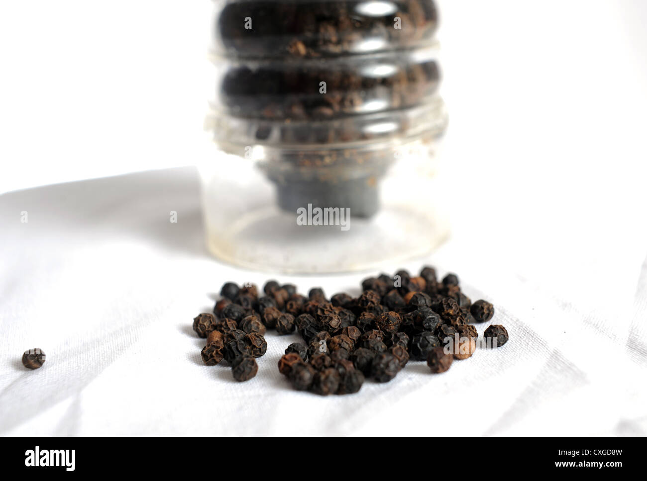 Black peppercorns and a see through plastic grinder or pepper mill UK