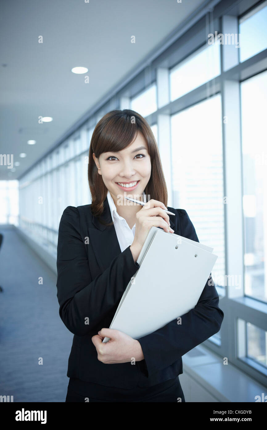 A business woman smiling with a folder in her arms Stock Photo - Alamy