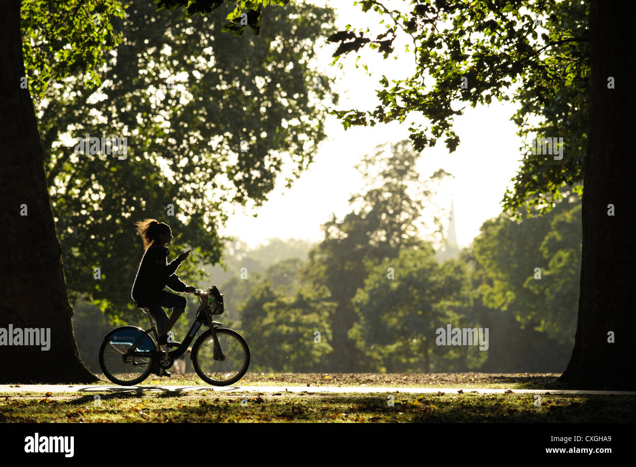 A young girl cycles whilst texting in Hyde Park Stock Photo Alamy