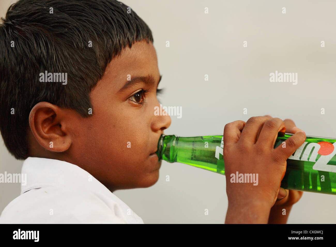 Indian school boy drinking a 7up soft drink Andhra Pradesh South India
