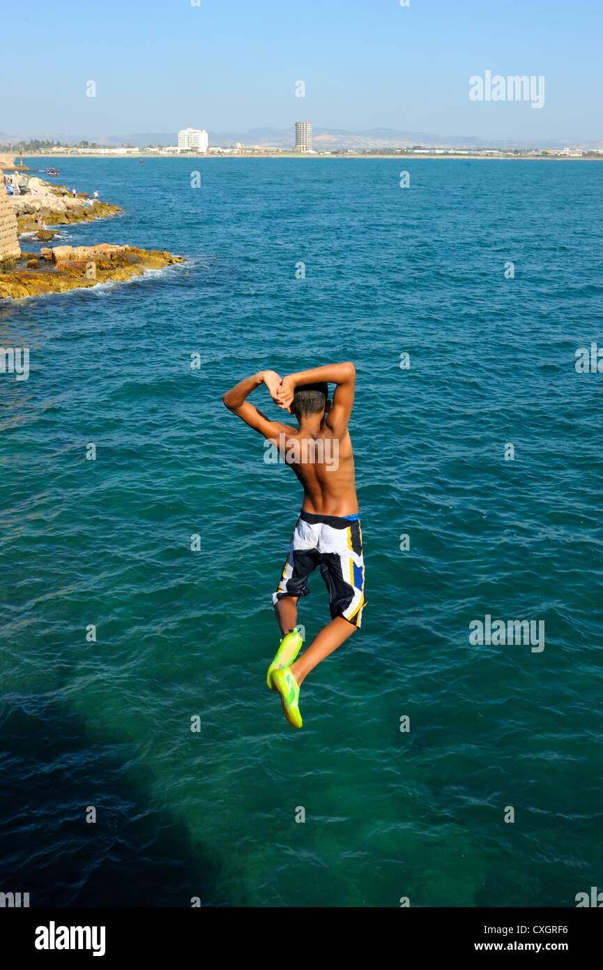 Teens, jumping into the sea from a height of city walls of Acre. Stock Photo