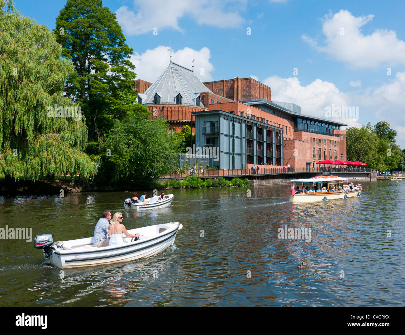 People in leisure boats on the river Avon next to the Royal Shakespeare Company Theatre, Stratford upon Avon, Warwickshire, UK Stock Photo