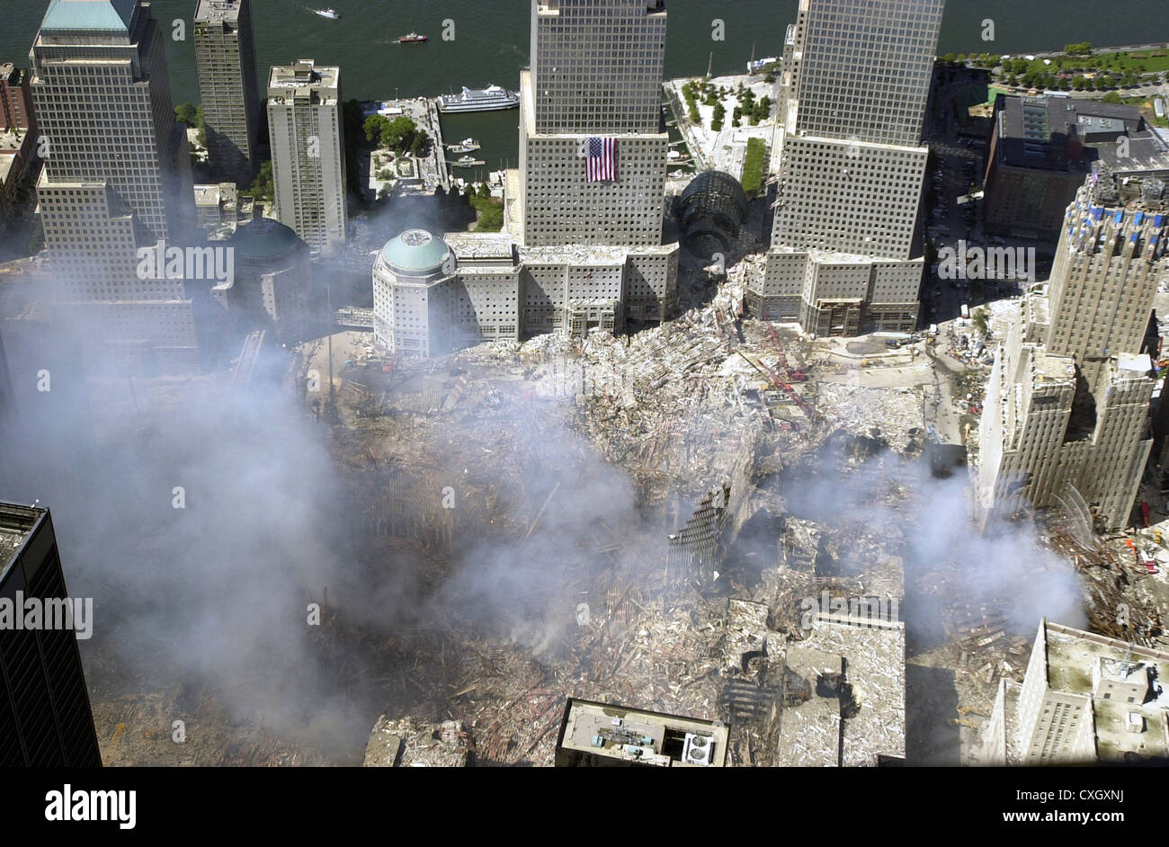 An aerial view of the destruction by terrorists of the World Trade Center September 15, 2001 in New York City. The view is to the west, with an American flag draped on one of the World Financial Center towers. The Hudson River is in the background. Stock Photo