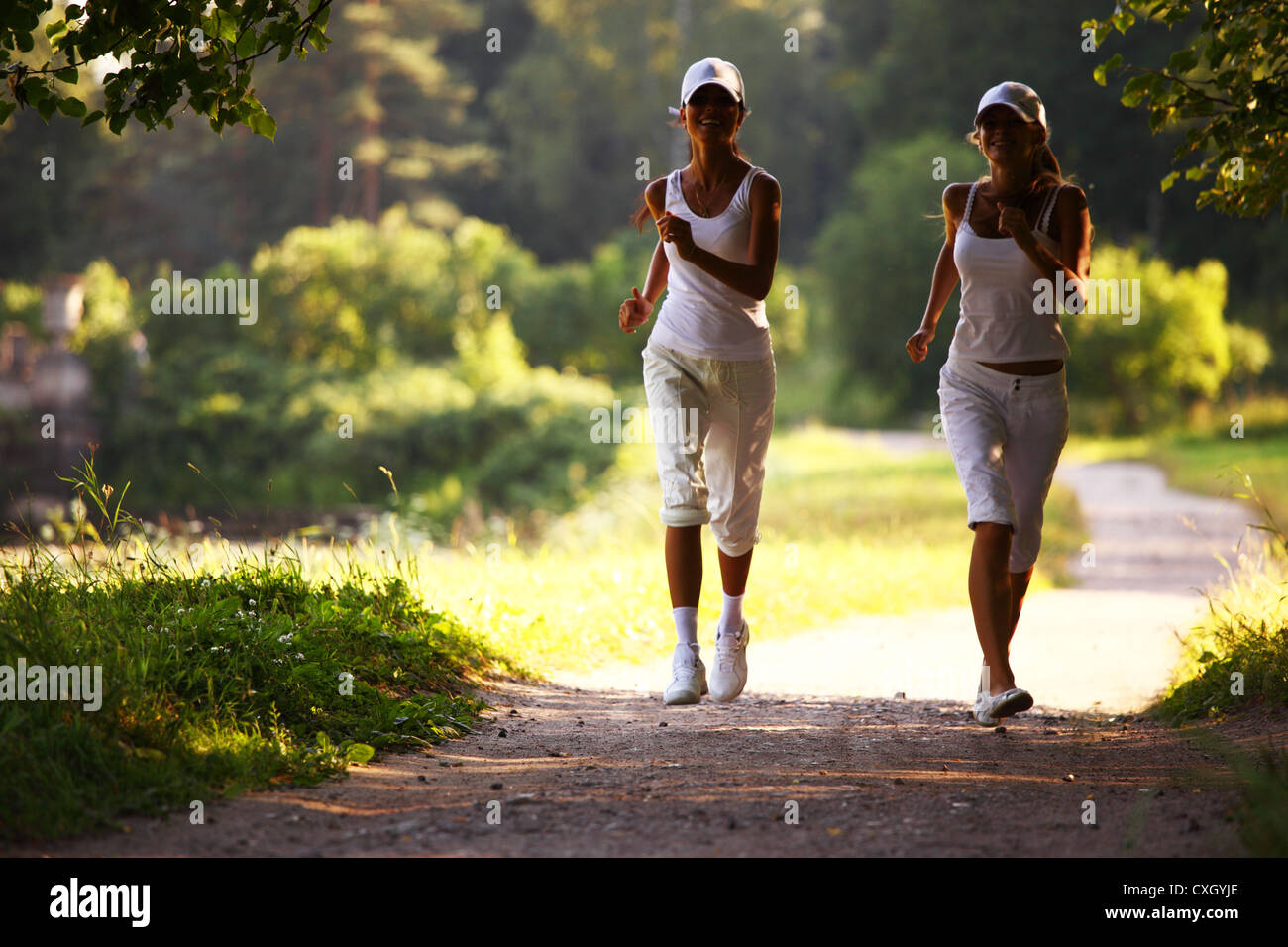 women run by sunny park alley Stock Photo Alamy