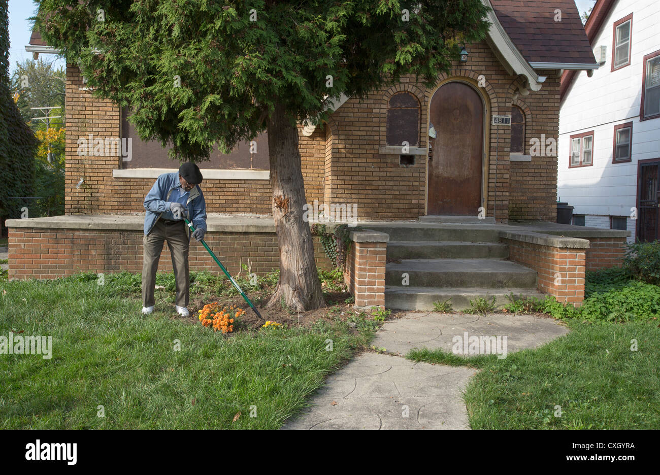 A member of the Three Mile Drive Block Club plants flowers in the yard of a boarded-up home. Stock Photo