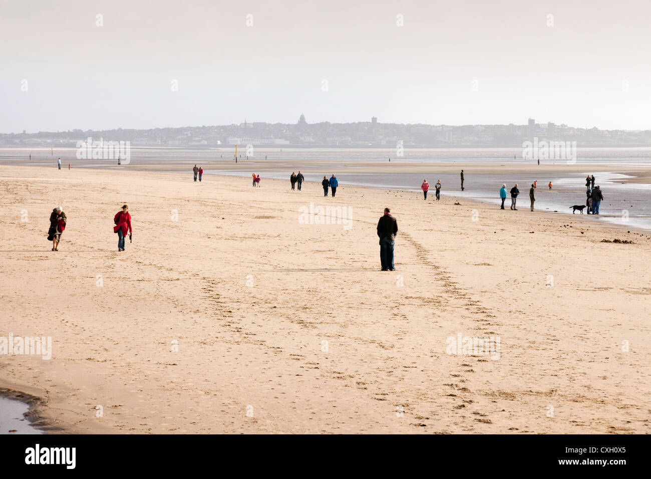 View of people walking on Crosby beach in the evening, Liverpool