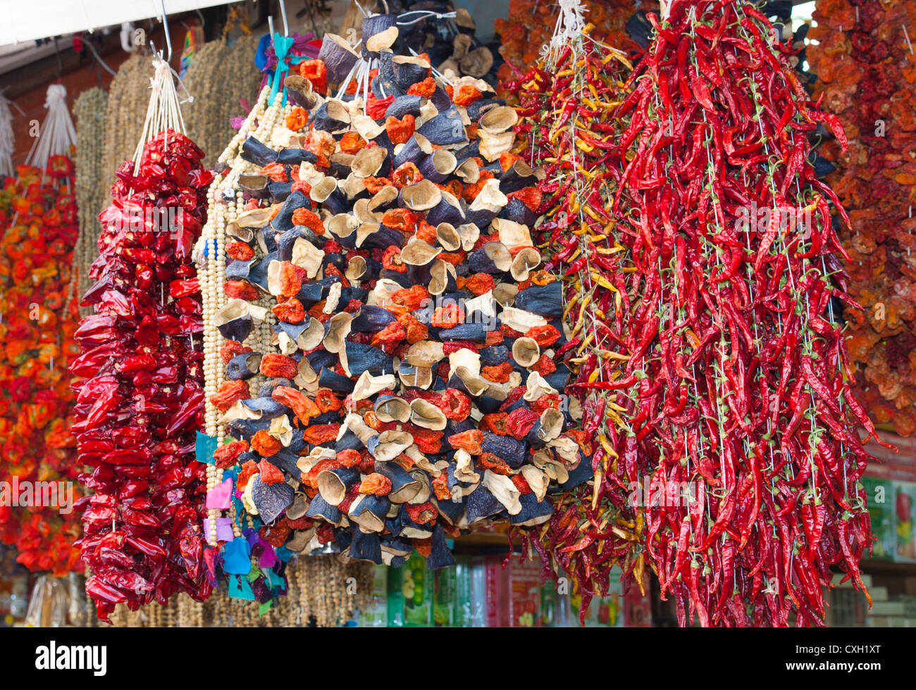 Bunches of dried vegetables hanging at an outdoor market stall Stock