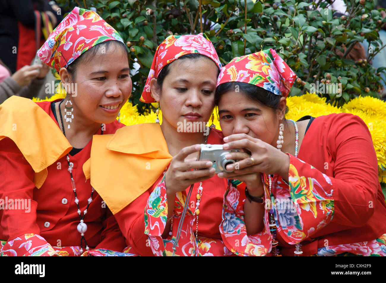 Hong Kong domestic helpers in traditional costume look at their photos during a New Year festival in Hong Kong Stock Photo