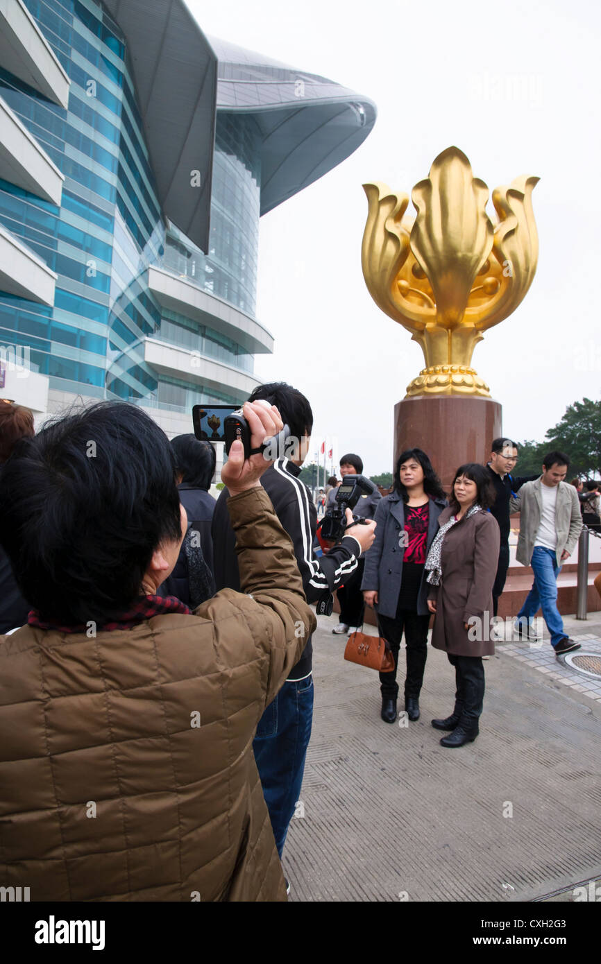 Mainland Chinese tourists pose for photographs next to the Golden Bauhinia sculpture, Hong Kong Stock Photo