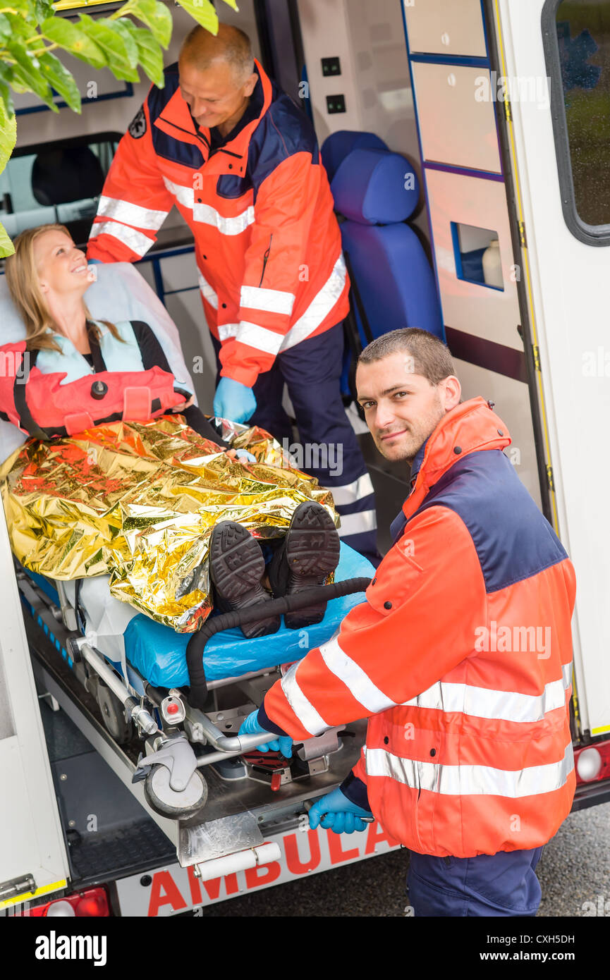Paramedics helping woman on stretcher in ambulance smiling accident ...
