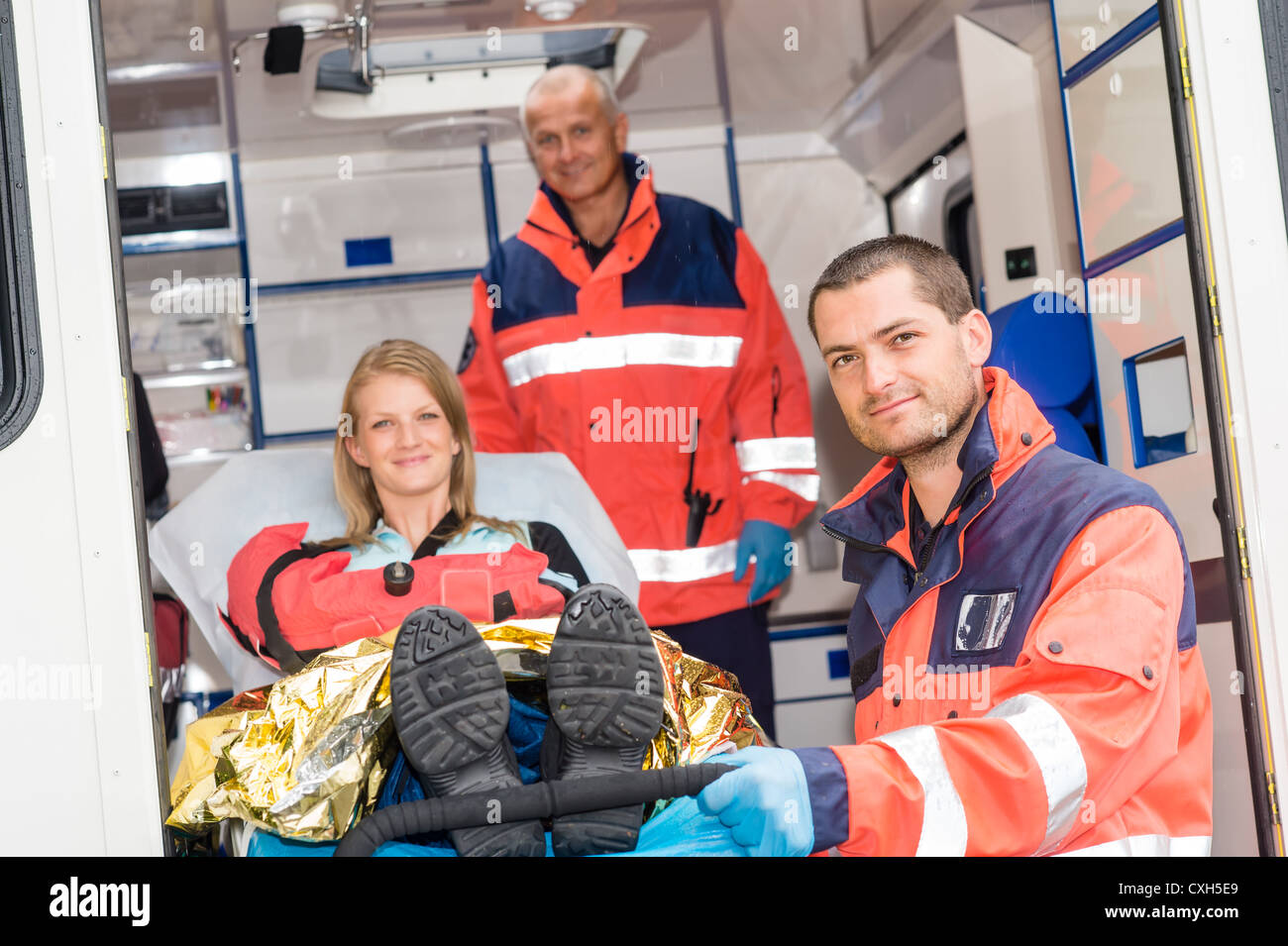 Paramedics helping woman on stretcher in ambulance smiling accident ...