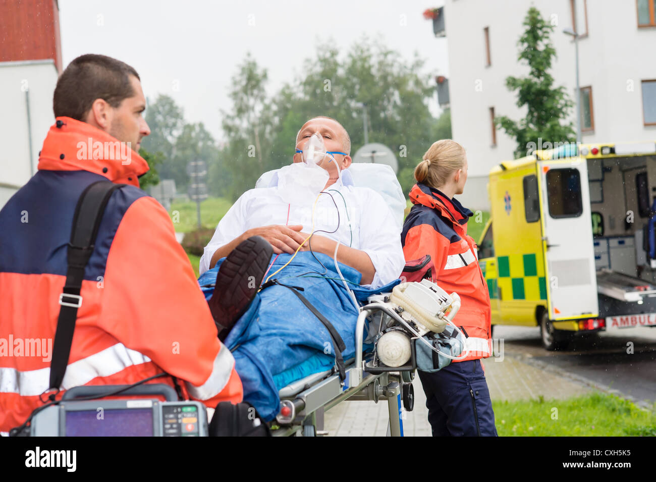 Paramedics with patient on emergency stretcher ambulance aid woman man ...