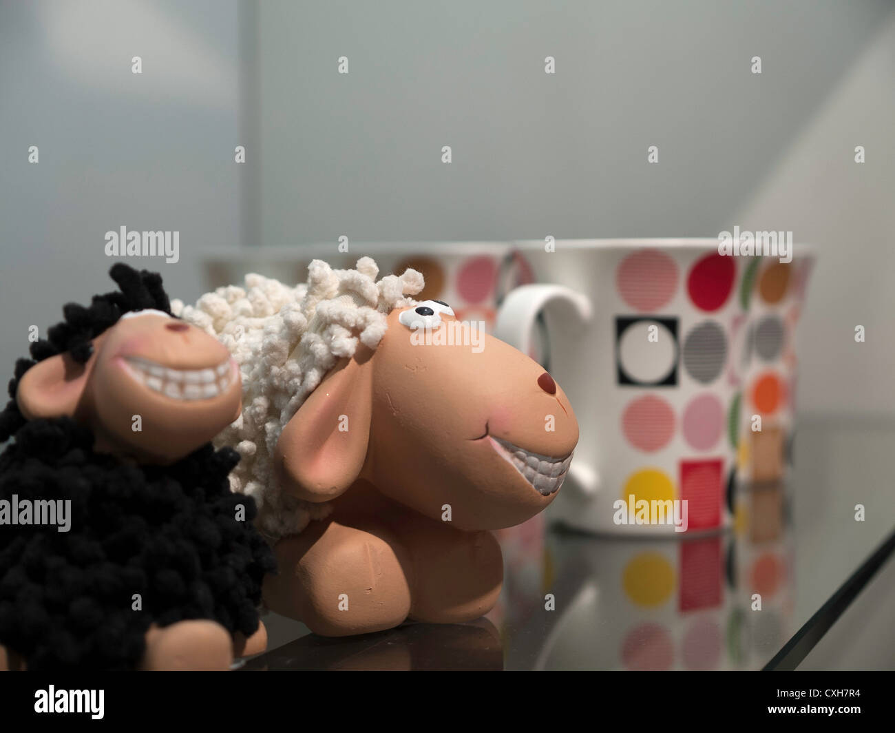 Shelf with porcelain colorful mugs and sheep toys Stock Photo