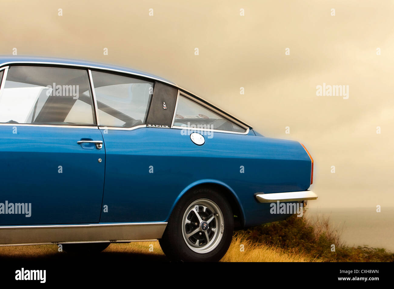 Sunbeam Rapier 1967-1976, blue car with chrome bumper and detailing parked on grass with sea and cloudy sky in background. Stock Photo