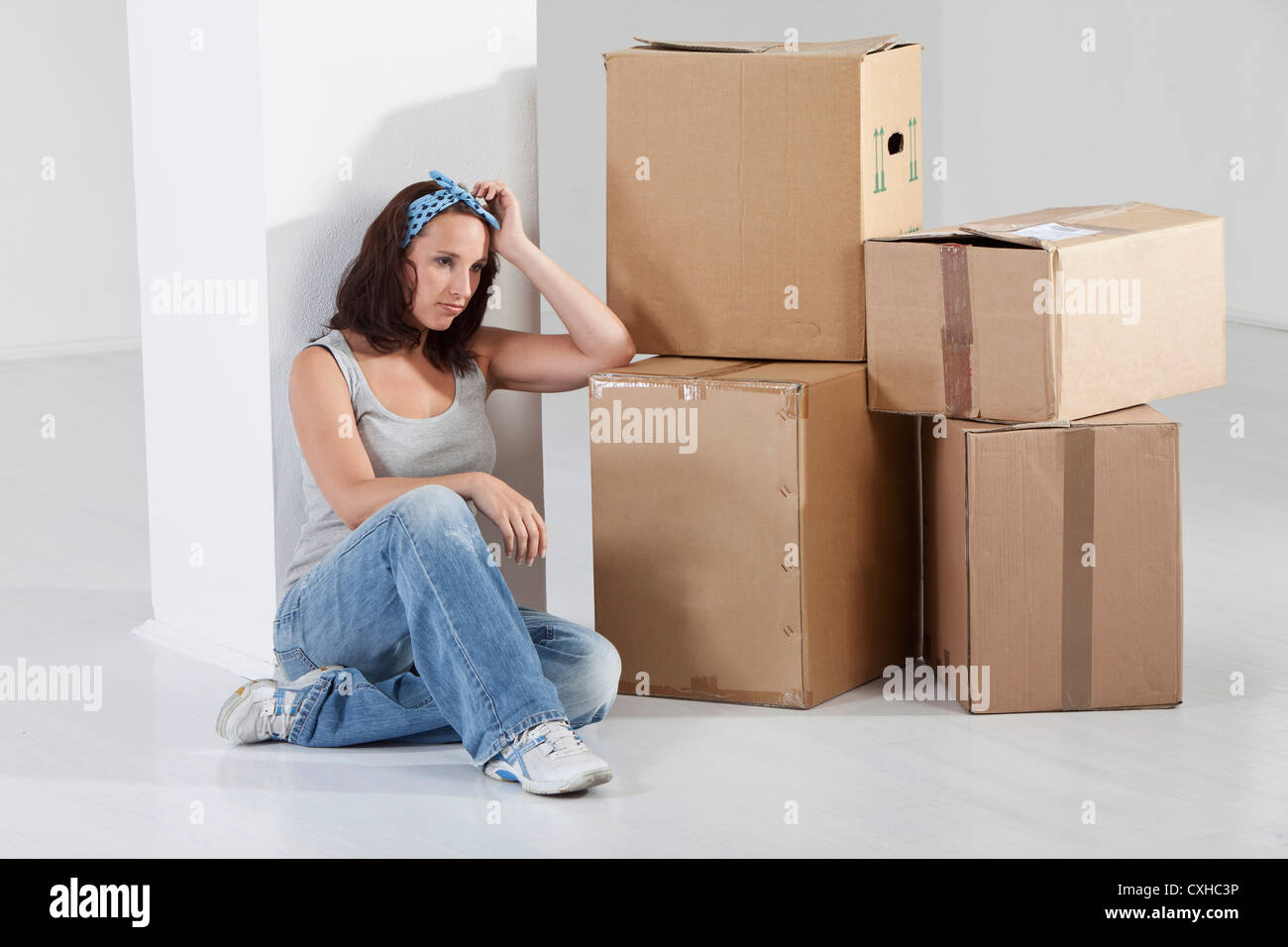 Young woman sitting by cardboard box Stock Photo - Alamy