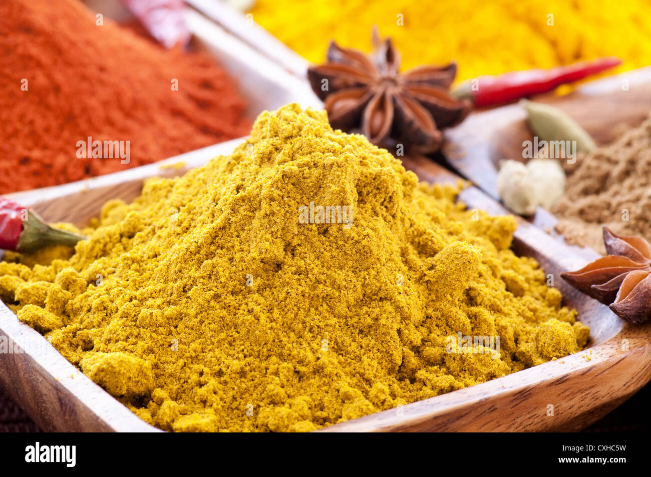 Exotically colorful spice mix with different podwer and grain in teak