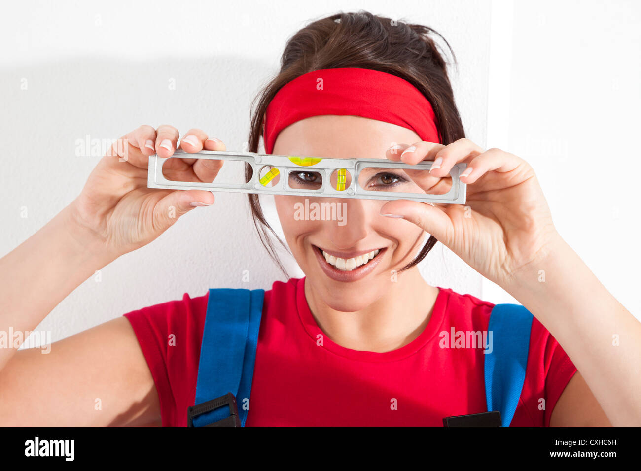 Germany, Bavaria, Young woman looking through spirit level Stock Photo