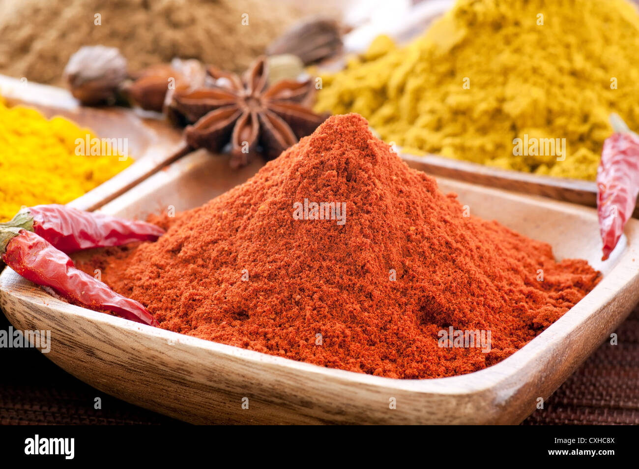 Exotically colorful spice mix with different podwer and grain in teak