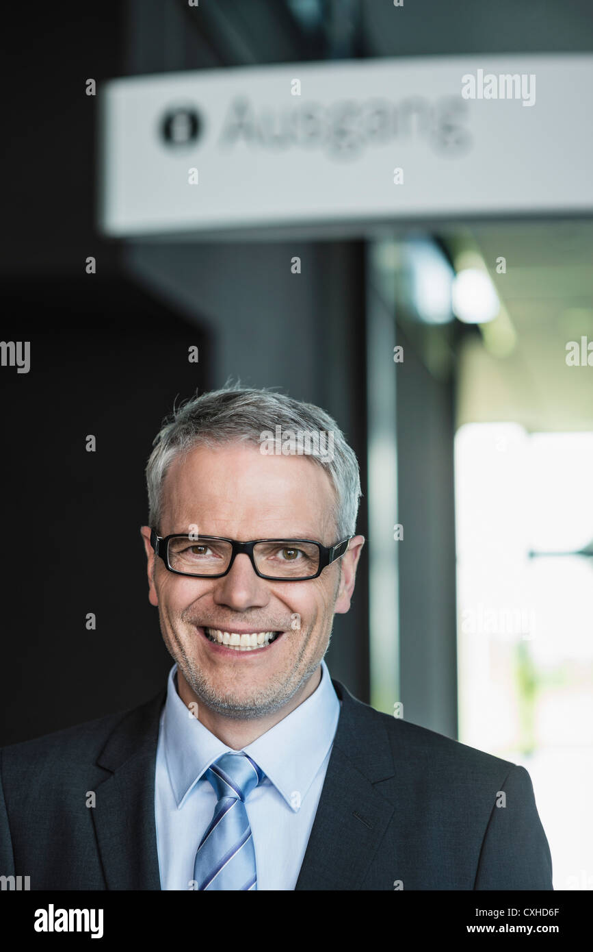 Germany, Stuttgart, Businessman standing in office building, portrait, smiling Stock Photo