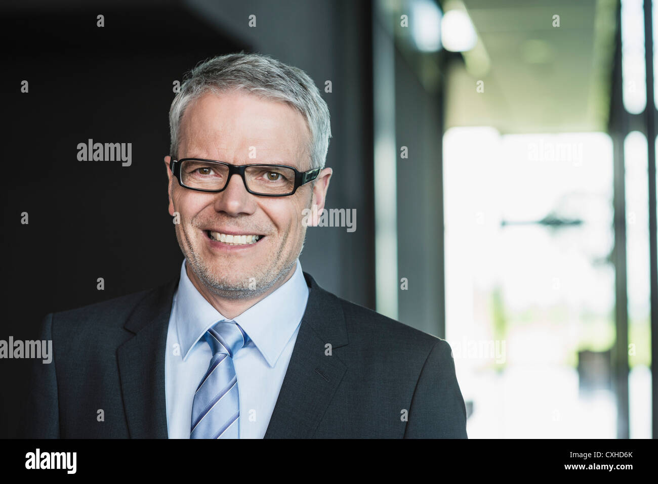 Germany, Stuttgart, Businessman standing in office building, smiling Stock Photo