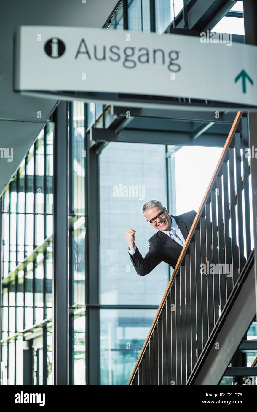 Germany, Stuttgart, Businessman moving up on office staircase, portrait, smiling Stock Photo